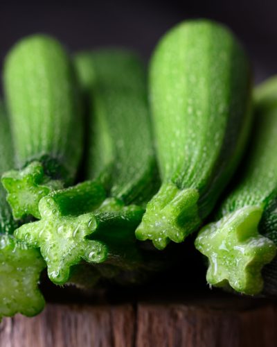 Close up of fresh green zucchini on wooden stump. Aesthetic food photography