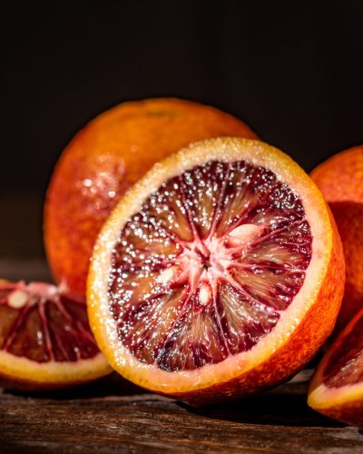 Whole and cut ripe juicy Sicilian Blood oranges on wooden background. Selective focus